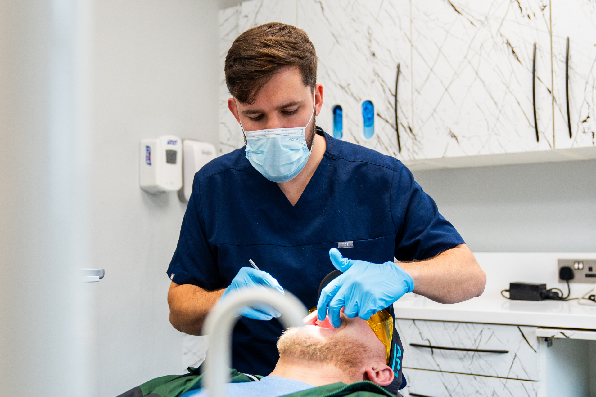 Dentist during dental treatment, wearing blue dental clothes